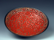 12. Thrown round bottomed dish with crawling coral red glaze and bronzes red volcanic banding.
