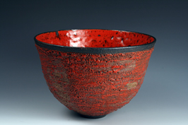 21. Large thrown form with red volcanic exterior and red crawling melt interior.